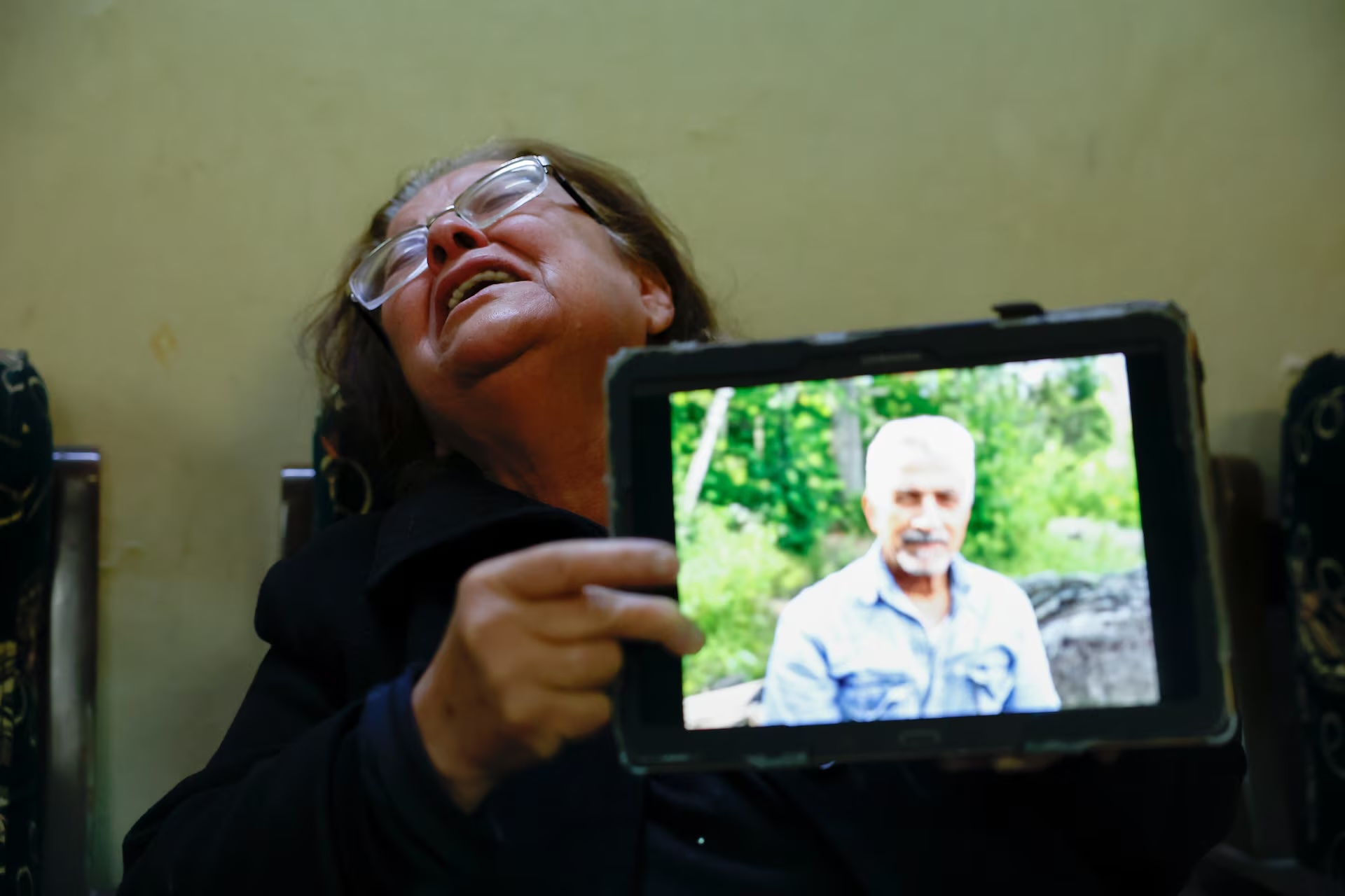 Самира Хадур показывает фотографию своего мужа, который был убит вместе с их взрослыми сыновьями в Джабле / Фото: Reuters